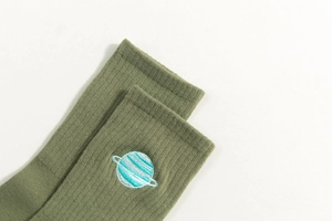 Close-up of olive green ribbed socks featuring a delicate blue and white planet embroidery