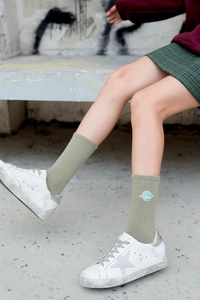 Close-up of green cotton mid-calf sock with blue planet embroidery and ribbed texture