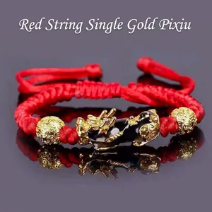 Close-up of golden PiXiu charm and beads on a hand-woven red cord bracelet