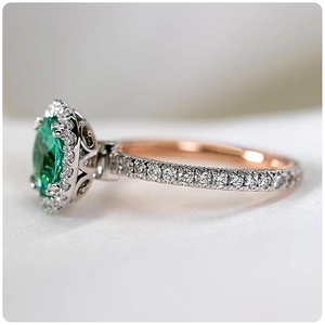 Elegant emerald ring with oval cut gemstone and cubic zirconia halo on rose gold band