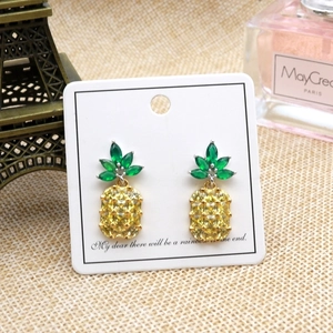 Detailed view of pineapple earrings with crystals on white display card with decor