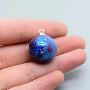 Detailed view of a galaxy nebula resin bead pendant with vibrant blue and purple swirls