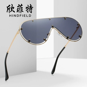Close-up of shield sunglasses with dark grey lenses and gold metal rivet details