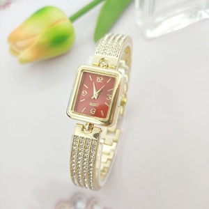 Elegant gold square watch with red dial and rhinestone-set metal strap on a floral backdrop