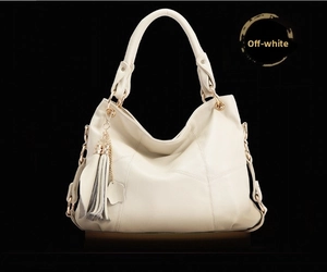 Detailed view of beige hobo handbag with tassel charm and elegant gold hardware