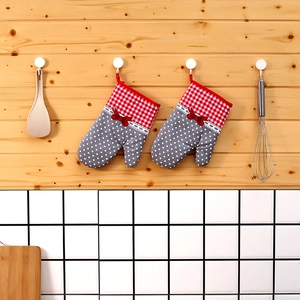 Close-up of thick plaid oven mitts with red bow detail hanging on a rustic wooden wall