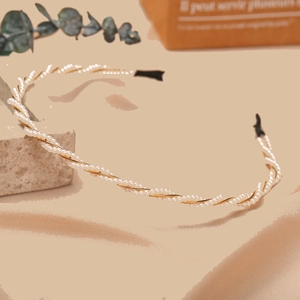 Detail of twisted white pearls on gold metal headband with elegant French retro style