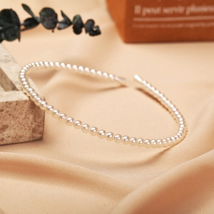 Elegant pearl headband with white round pearls on a slim gold metal base in vintage style