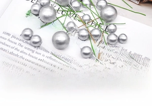 Macro shot of silver pearl craft berries with wire stems on vintage paper background