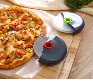 Dual circular pizza cutters with red and green handles on a wooden board with pizza