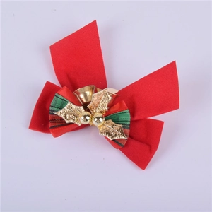 Detail of red Christmas bow with golden bell, holly leaves and green plaid ribbon