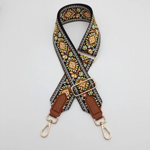 Detail of bohemian embroidery on adjustable canvas strap with gold metal lobster hooks