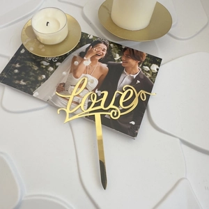 Close-up of golden acrylic love cake topper for romantic wedding and party decoration