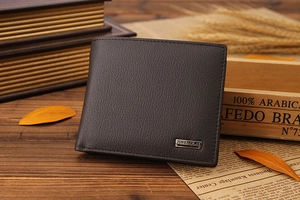 Detail of dark brown leather bi-fold wallet with pebble texture and metallic brand logo