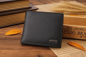 Detail of bifold leather wallet with metal logo on rustic wooden table background