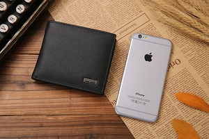 Short black leather men's wallet with lychee grain next to an iPhone for size comparison