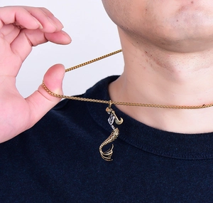 Detailed view of a gold mermaid pendant necklace worn by a model against white background