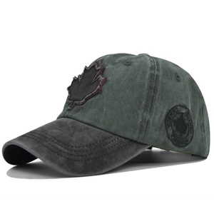 Detail of vintage green washed cotton baseball cap with maple leaf and side badge