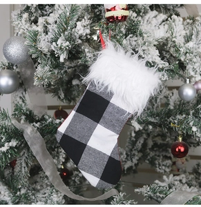 Close-up of a buffalo plaid Christmas stocking with faux fur cuff hanging on a snowy tree