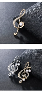 Detailed view of music note brooches with white rhinestones and pearls on black leather