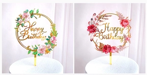 Detail of gold acrylic Happy Birthday cake toppers with floral and feather accents