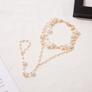 Detail of bohemian gold chain anklet with white faux pearls on textured fabric