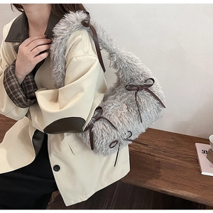 Close-up of plush grey shoulder bag with brown bow and silver butterfly buckle detail
