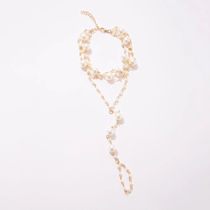 Detail view of a bohemian multi-layer gold pearl anklet and toe ring set on white background