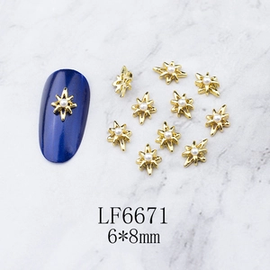 Detail of 6x8mm gold star nail charm with central pearl on marble background