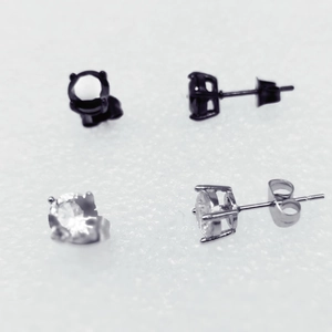 Detail view of four-prong round zircon stud earrings in black and silver finishes
