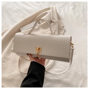 Detail of white woven textured baguette bag with gold metal clasp and long strap