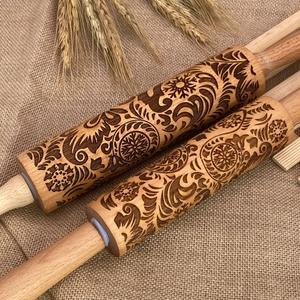 Two wooden Christmas rolling pins with laser engraved floral patterns on burlap background