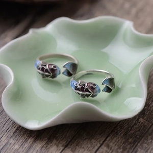 Detailed view of Koi fish enamel rings with gradient scales on a decorative ceramic plate