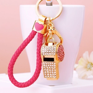 Detailed close-up of golden rhinestone whistle keychain with pink braided cord