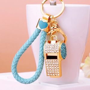 Detailed close-up of crystal-studded whistle keychain with blue braided rope strap