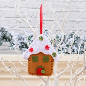 Detailed plush gingerbread house ornament with red ribbon hanging on a white branch