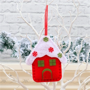 Detail of red fabric house ornament with white roof hanging on a winter branch