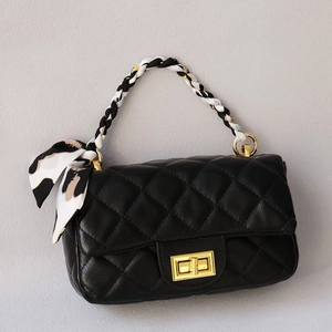 Black quilted handbag with silk scarf handle and gold twist lock in minimalist style