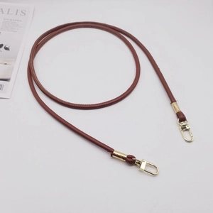 Close-up of brown PU leather shoulder strap with golden metal swivel hooks and retro coil wrap