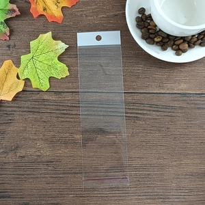 Clear long OPP plastic self-adhesive packaging bag with hanging hole on a wood background