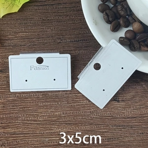 Detail view of white 3x5cm earring display cards with Fashion text on wood background