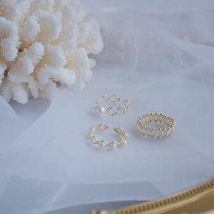 Detailed view of three gold-plated rings with natural freshwater pearls and beaded textures