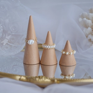 Three elegant gold-plated rings with natural freshwater pearls on wooden display cones