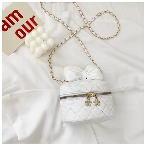 Detailed macro view of white quilted mini crossbody bag with a large bow and gold chain