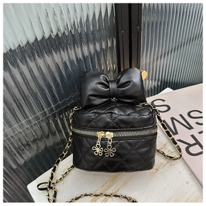 Detail of quilted PU leather mini bag with bow accent and flower zipper pull on gold chain