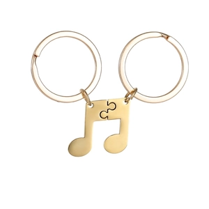 Detailed close-up of split musical note couple keychains in a polished gold finish