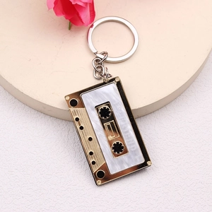 Macro detail of a vintage gold tape keychain with white pearl panel and I ♡ FRIEND engraving