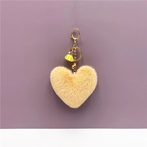 Detail view of heart-shaped yellow faux fur keychain with gold clasp and tassel