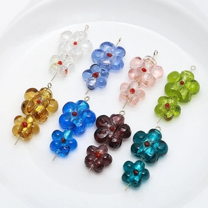 Handmade glass flower charms with gold dust in eight colors on a white plate
