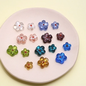 Handmade glass flower beads in various colors for DIY jewelry making on a pink plate